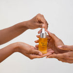 Hands holding Lilac + Flint Glow serum 
