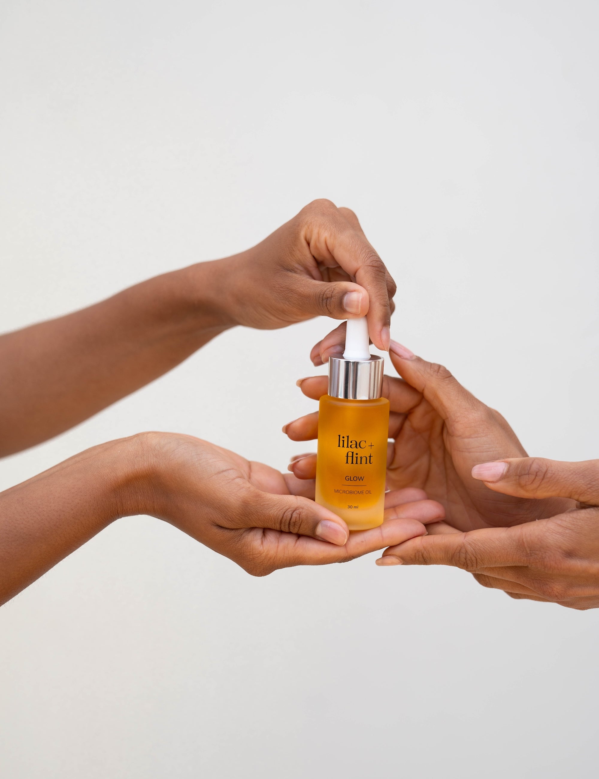 Hands holding Lilac + Flint Glow serum 