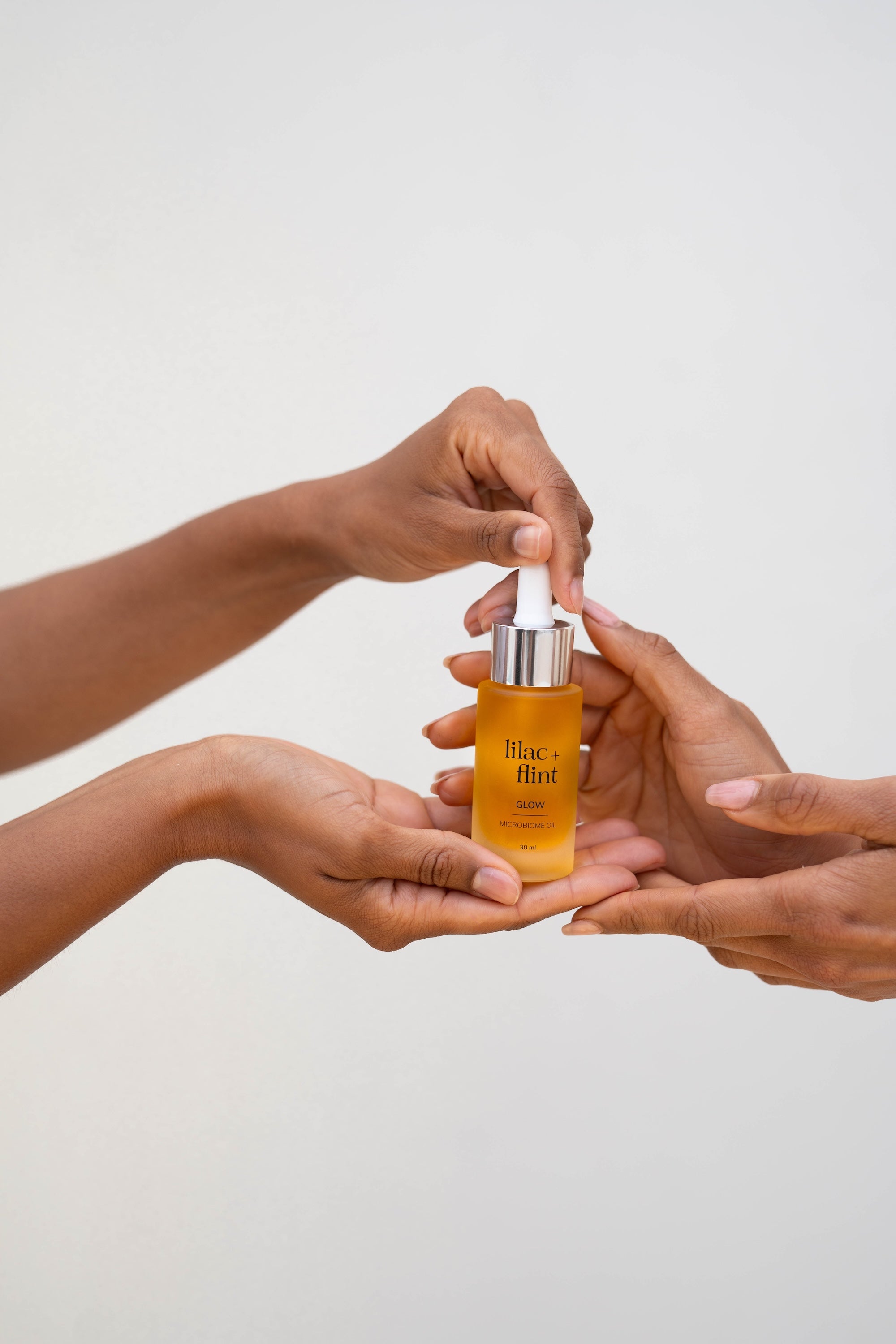 Hands holding Lilac + Flint Glow serum 